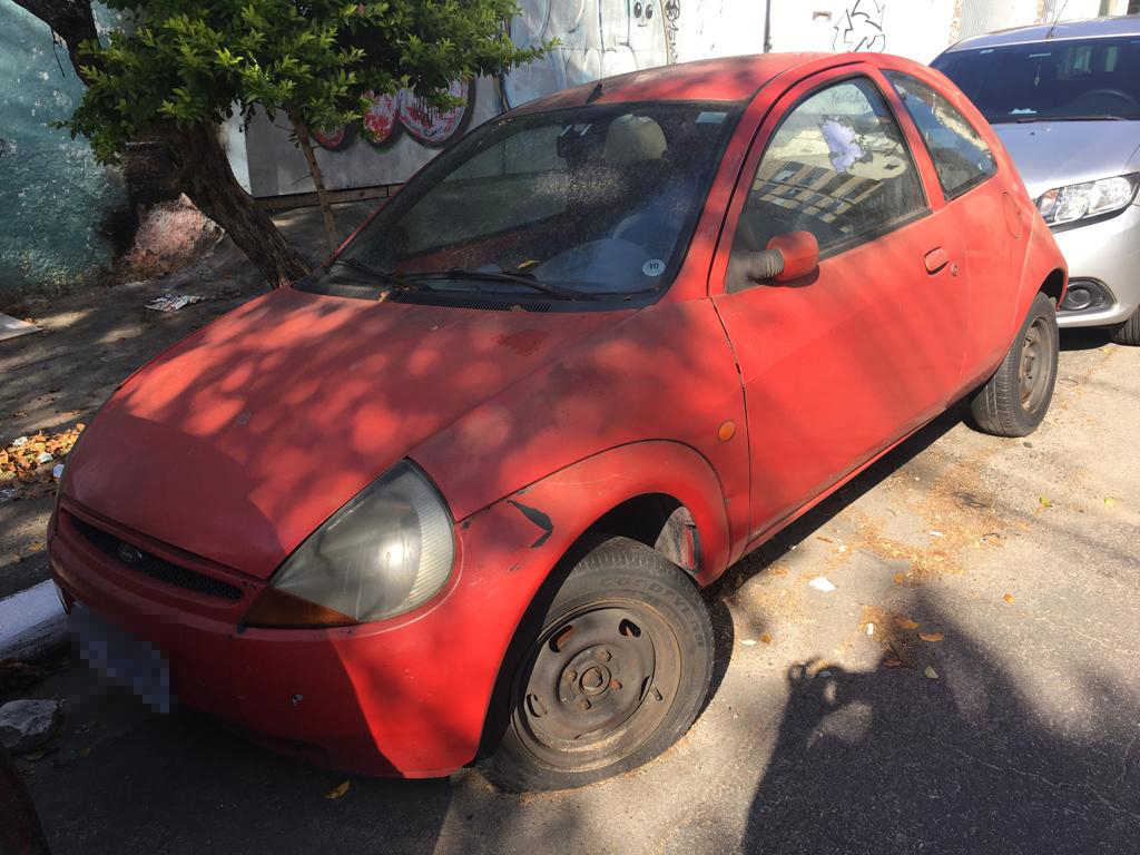 Lateral do carro vermelho abandonado na rua 